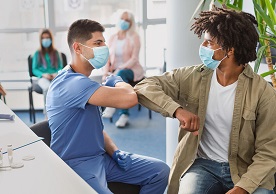 medical assistant administering COVID vaccine to a person of color